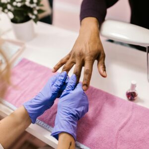 A professional manicure service in action with latex gloves and colorful nail polish.
