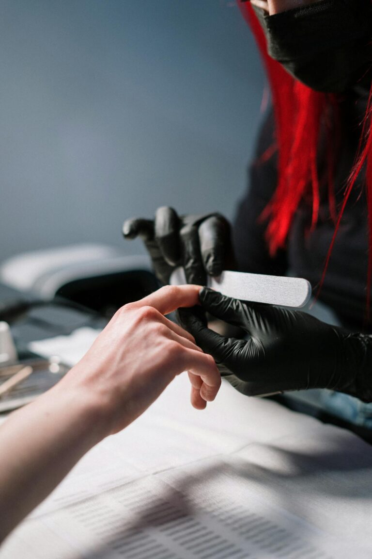 Close-up of a professional manicurist providing nail care with black gloves.